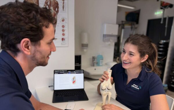 Physiotherapeutin Valentina Nussbaumer erklärt Daniel Ragger ein Kniemodell in der PureMotion Praxis in 1220 Wien.