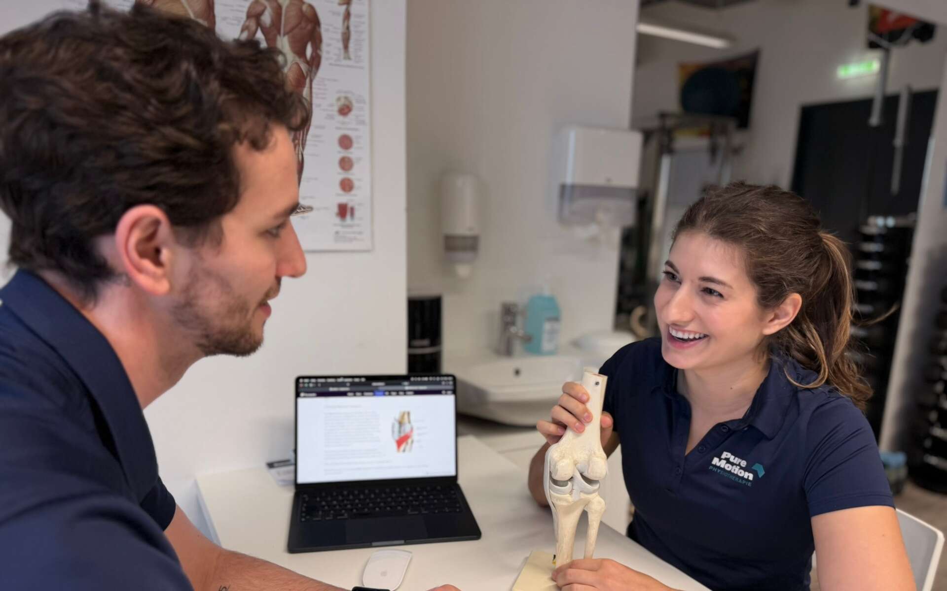 Physiotherapeutin Valentina Nussbaumer erklärt Daniel Ragger ein Kniemodell in der PureMotion Praxis in 1220 Wien.